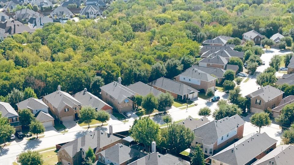 A residential area with houses, trees, and a clear sky.