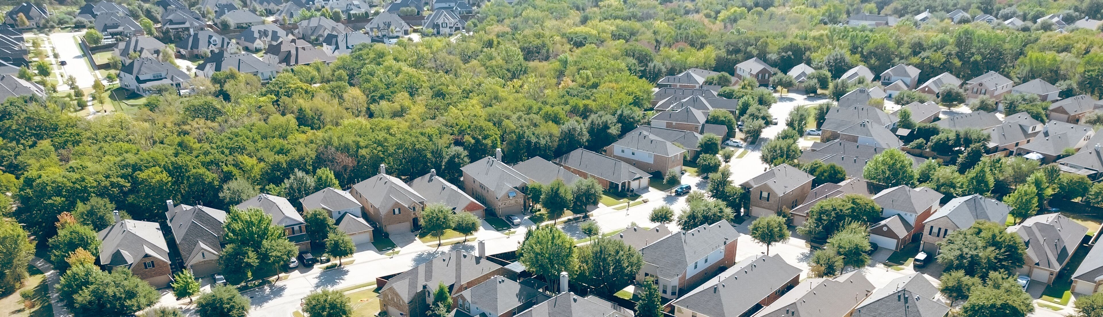 A residential area with houses, trees, and a clear sky.