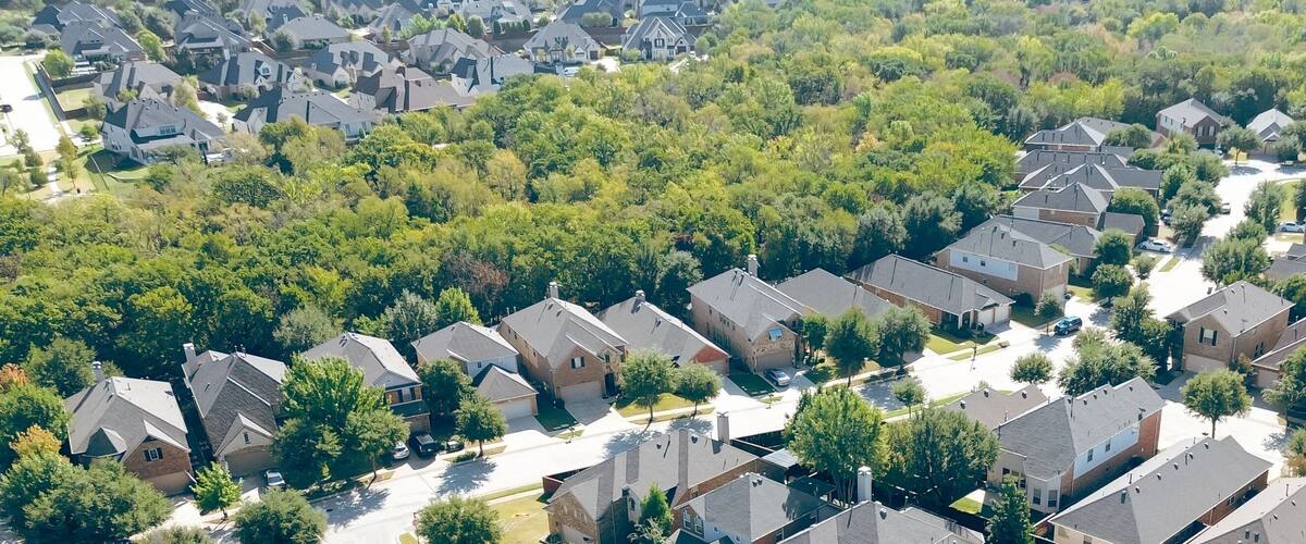 A residential area with houses, trees, and a clear sky.