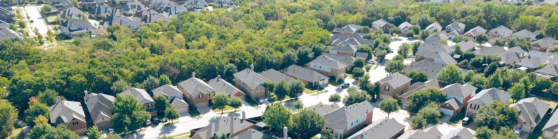 A residential area with houses, trees, and a clear sky.