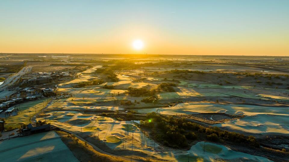 A golf course with a sunset in the background.