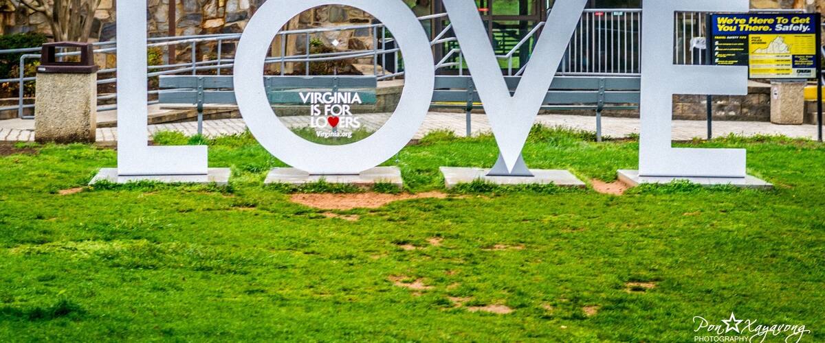 A large LOVE sign in front of a building with a stone facade and a sign that reads "Virginia is for Lovers."