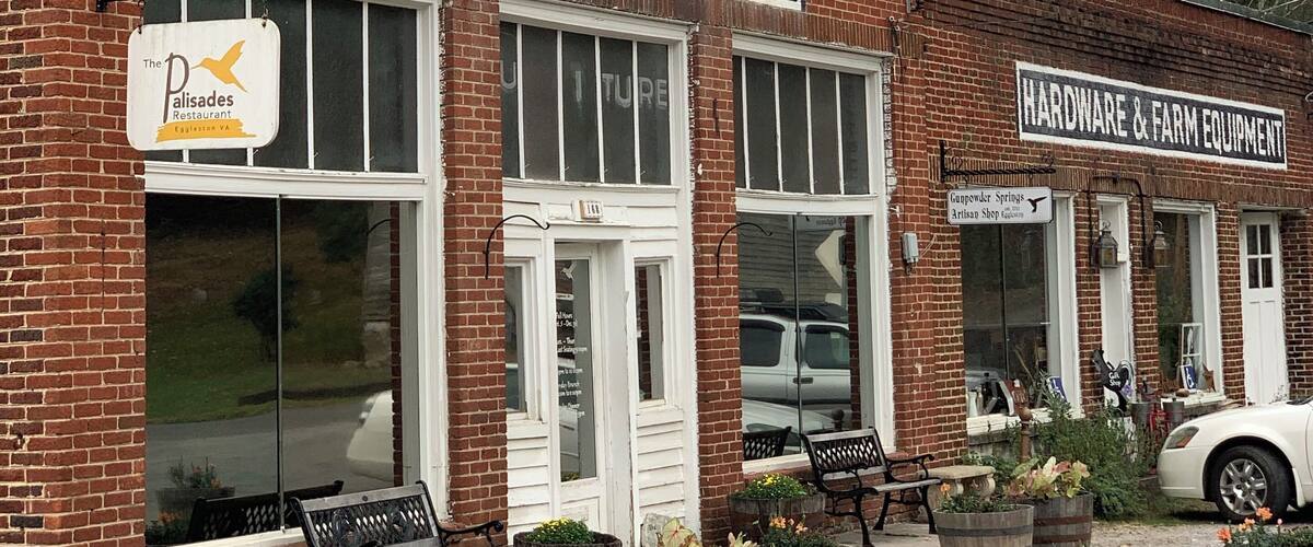 A brick building with signs for Q.M. Pyne MDSE, a restaurant, and a hardware store.