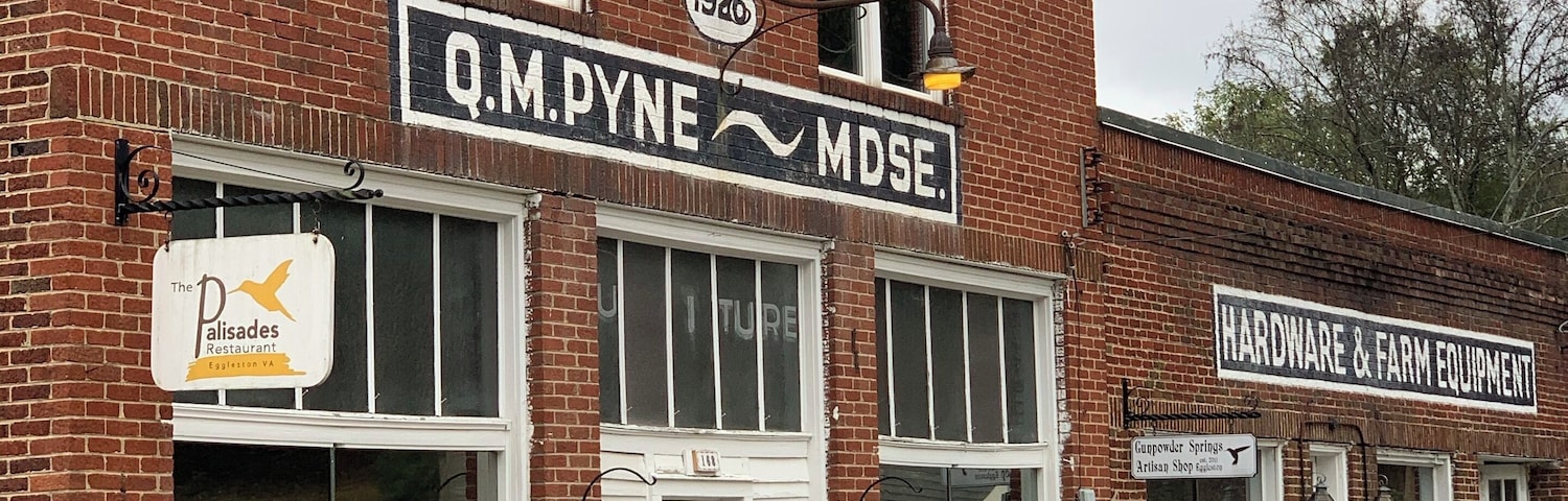 A brick building with signs for Q.M. Pyne MDSE, a restaurant, and a hardware store.