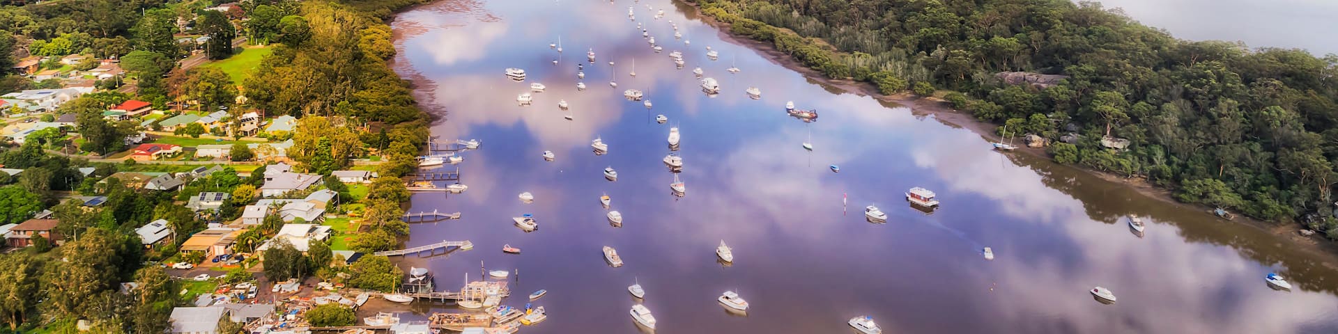 A river with numerous boats, a bridge, and a town on the banks.