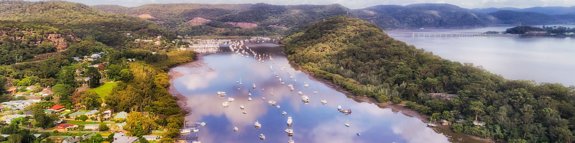 Um rio com vários barcos, uma ponte e uma cidade nas margens.