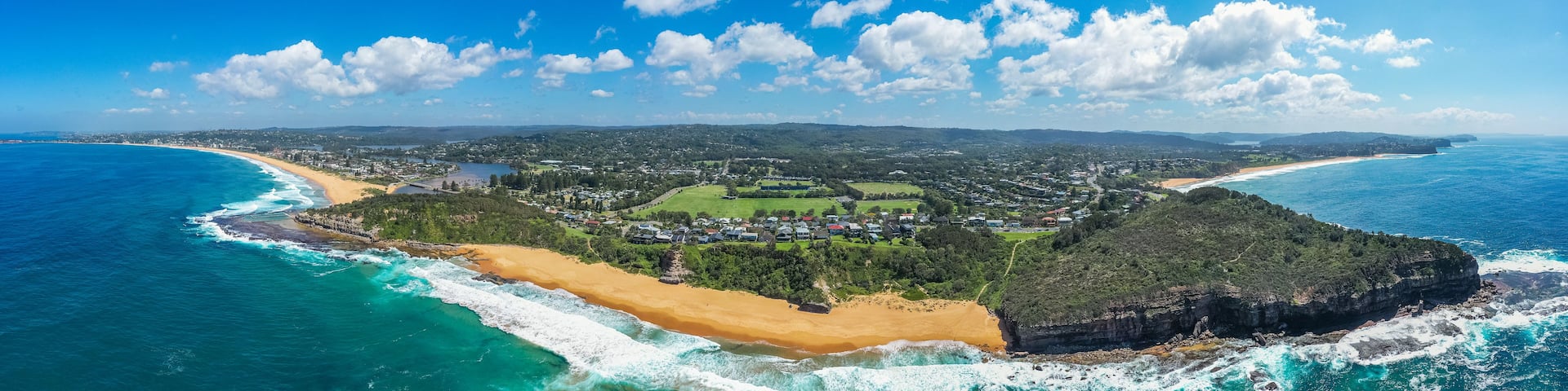 A coastal town with a beach, ocean, and surrounding hills.