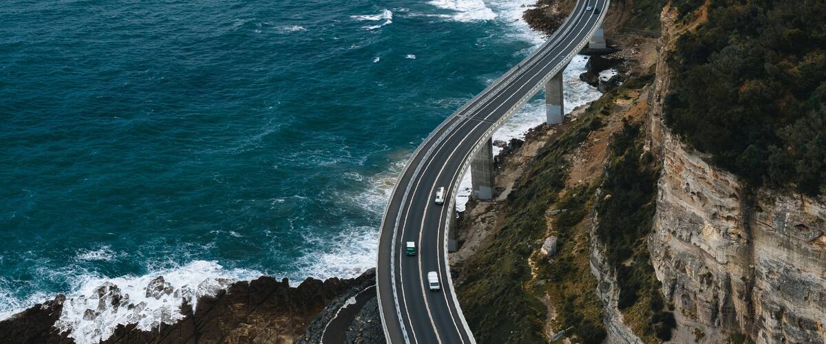 Una carretera costera serpenteando a lo largo de un acantilado con el océano al fondo.