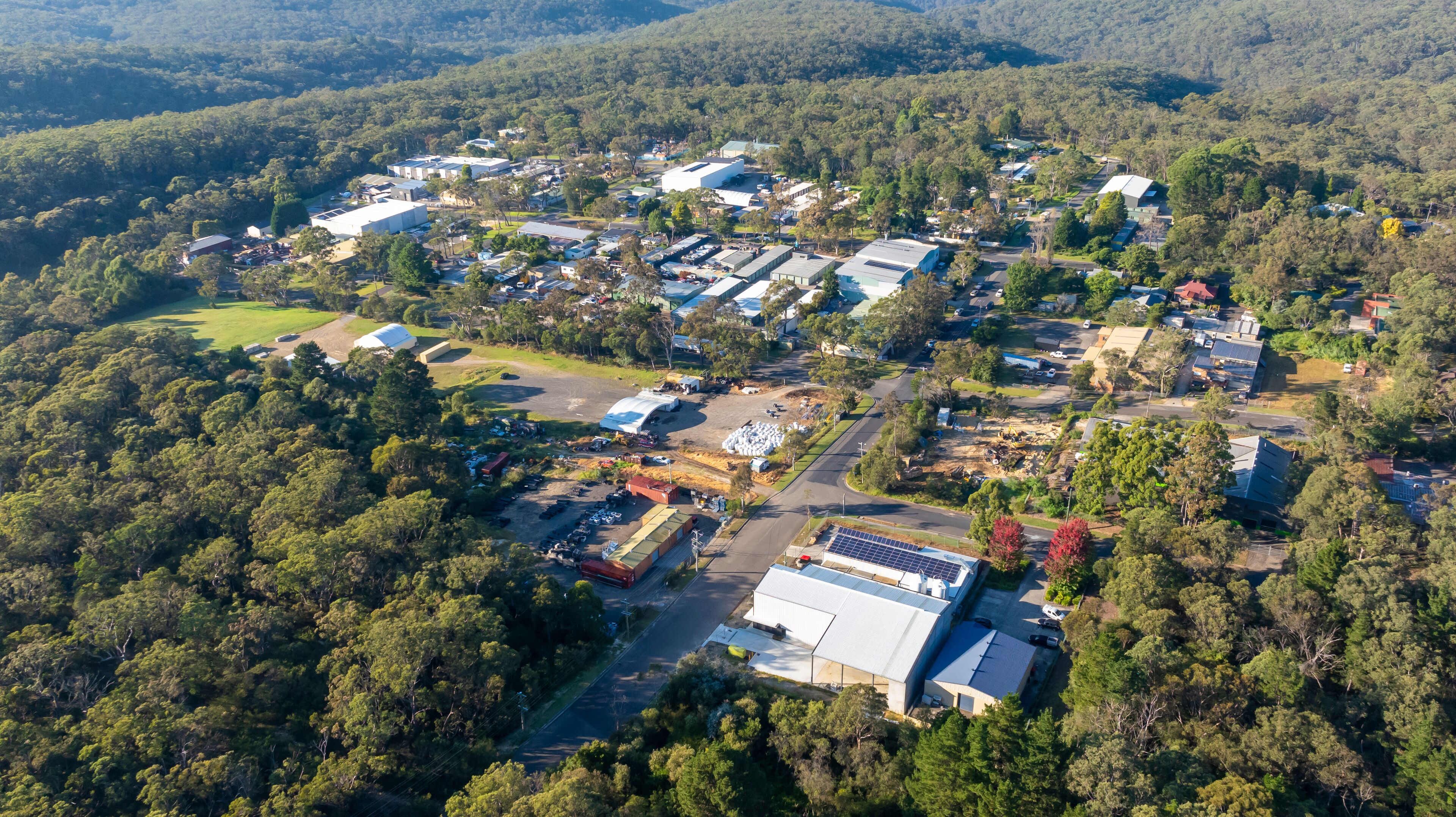 An aerial view of a residential area with houses, roads, and surrounding forest.