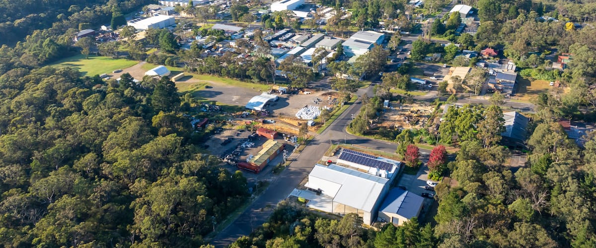 An aerial view of a residential area with houses, roads, and surrounding forest.