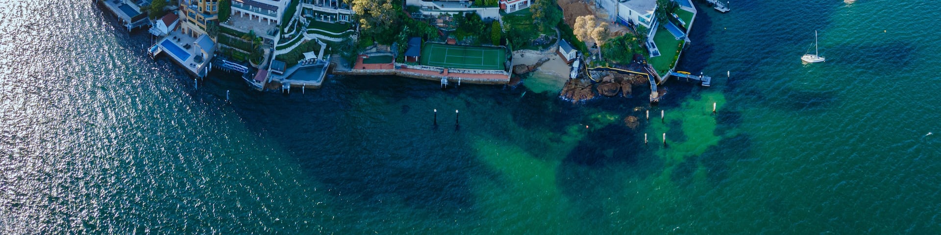An aerial view of a coastal town with dense housing, a marina, and a bay.