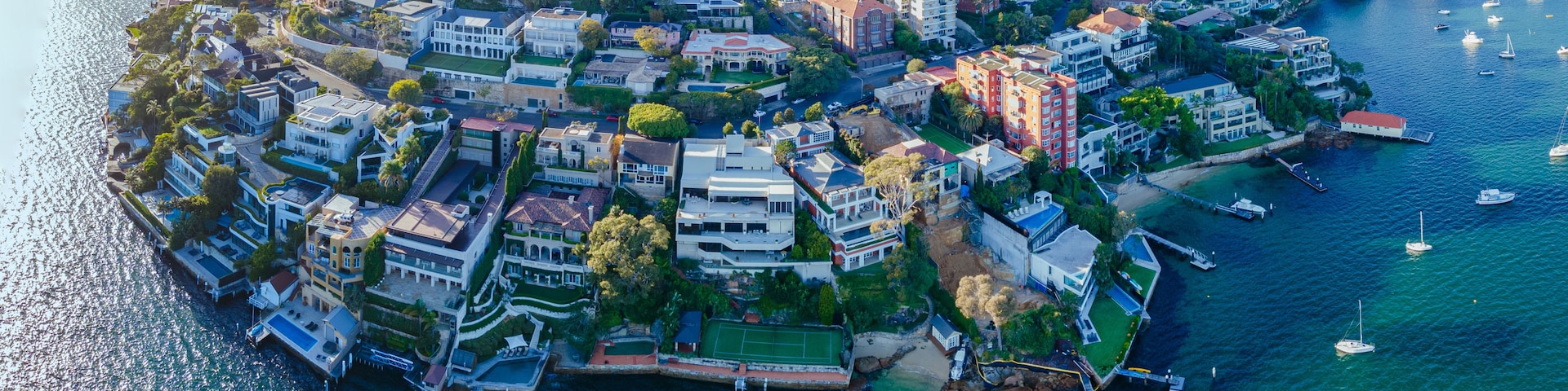 Vista aérea de uma cidade costeira com habitação densa, um porto de iates e uma baía.