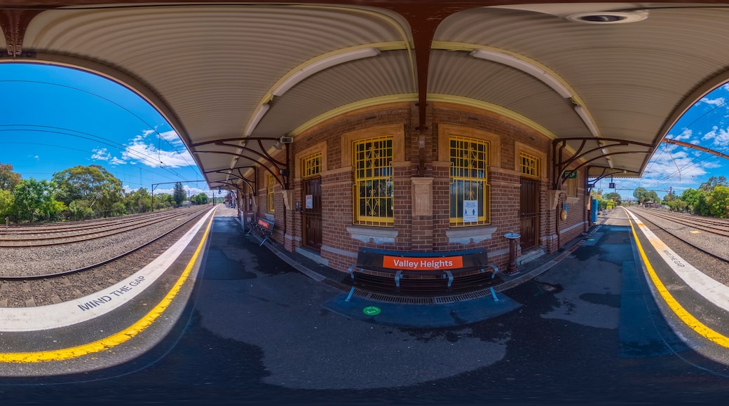 Una estación de tren con un andén curvo, paredes de ladrillo y ventanas amarillas.