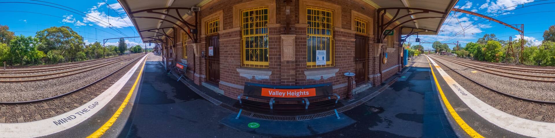 A train station with a curved platform, brick walls, and yellow windows.