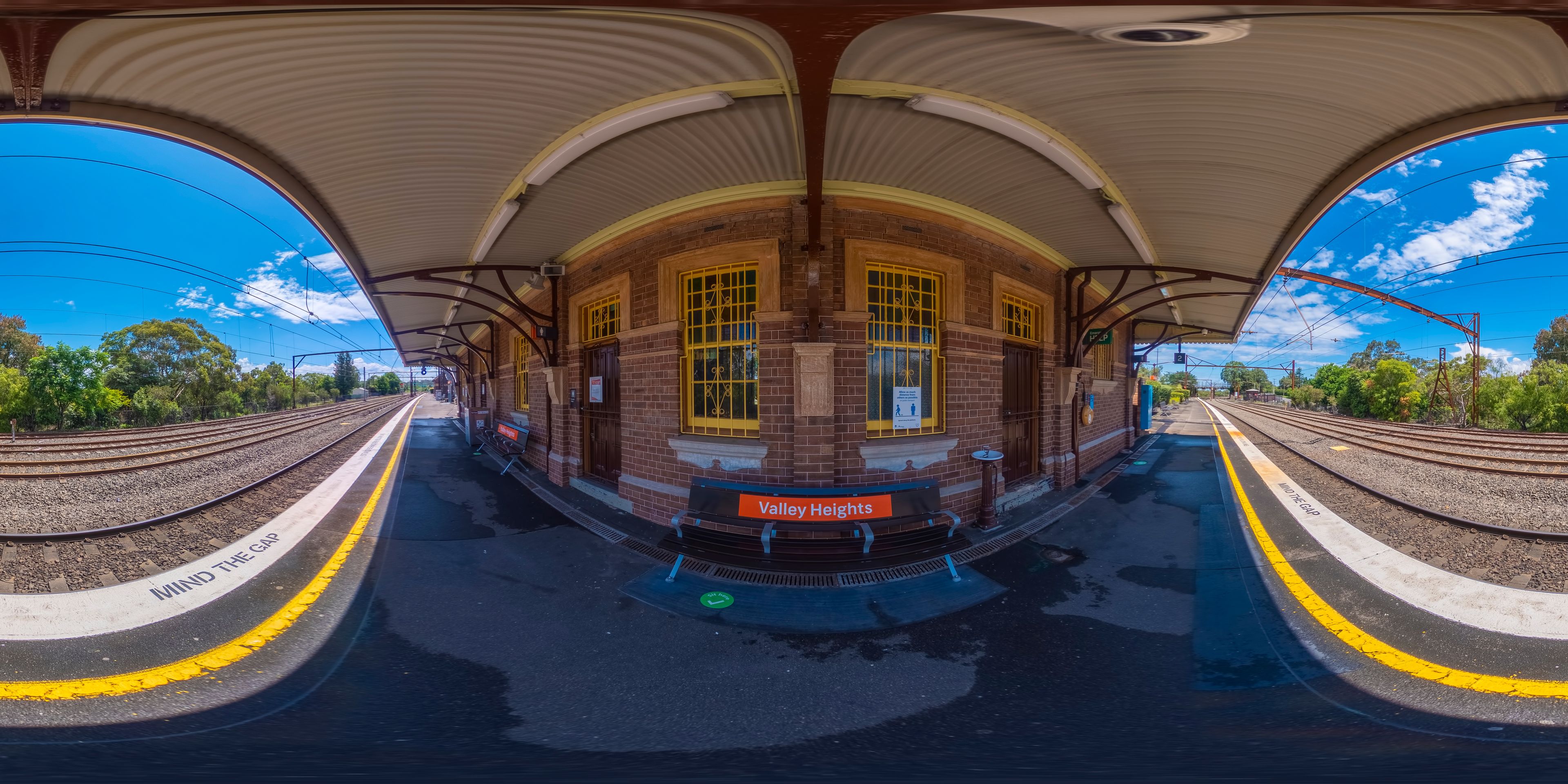 A train station with a curved platform, brick walls, and yellow windows.
