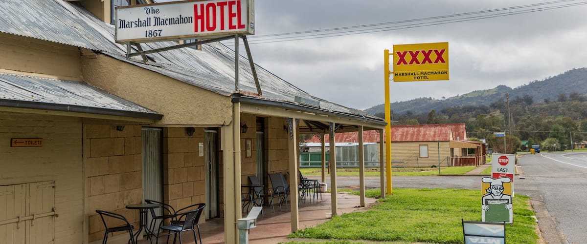 A historic hotel with outdoor seating and a signboard.