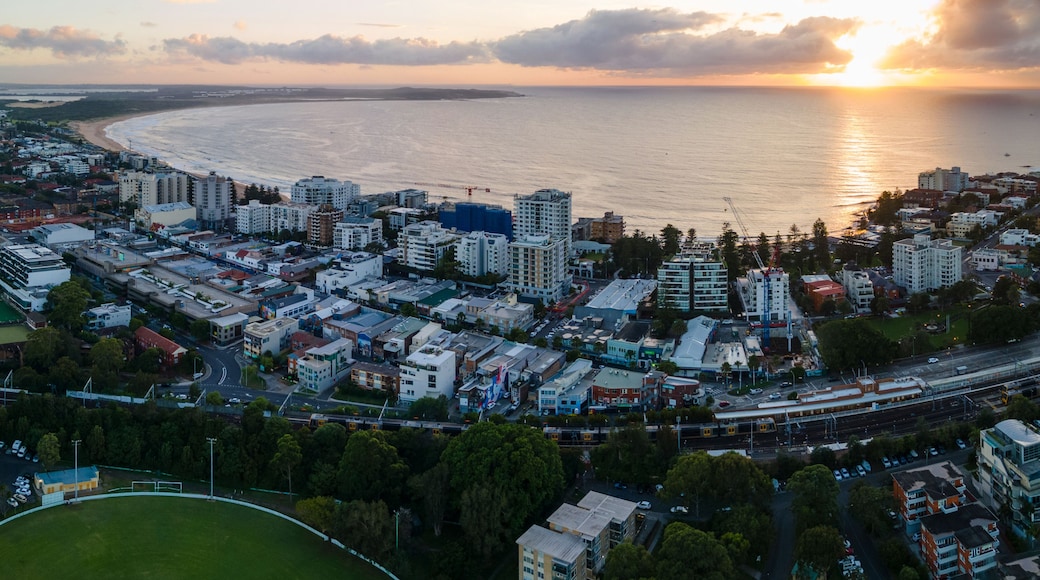 A coastal cityscape with a beach, buildings, and a sunset.