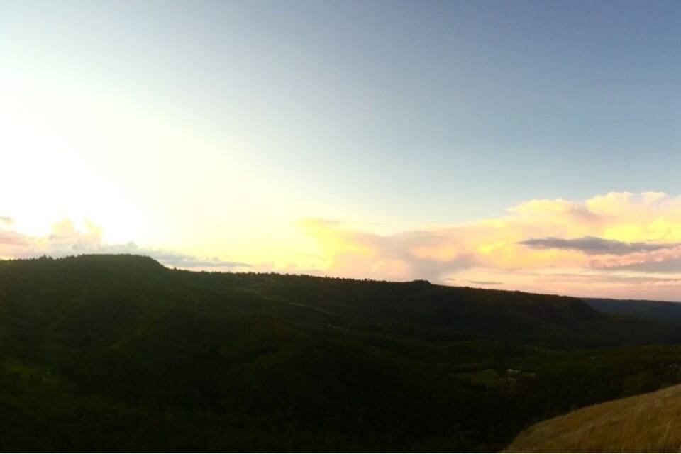 A landscape with rolling hills and a sunset.