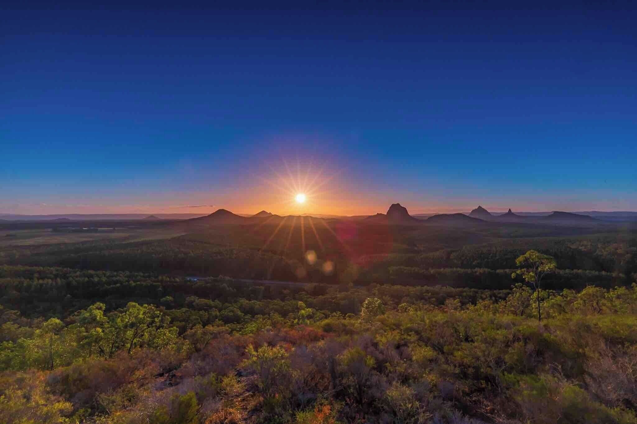A sunset over a mountainous landscape with a clear sky.