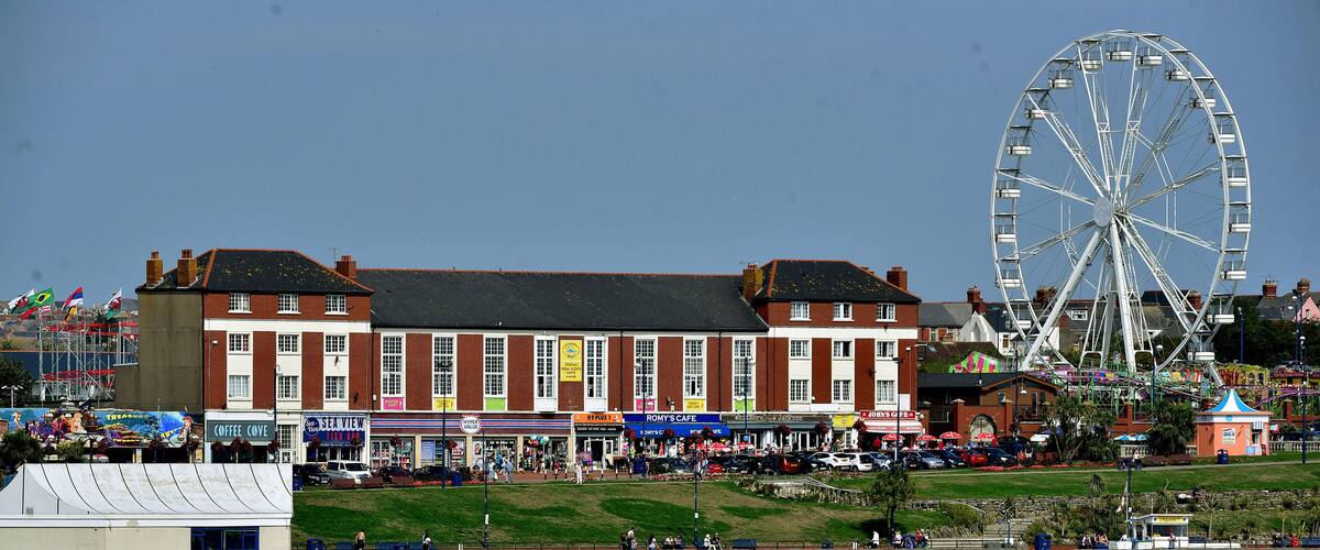 A beach with a Ferris wheel and a historic building with shops.