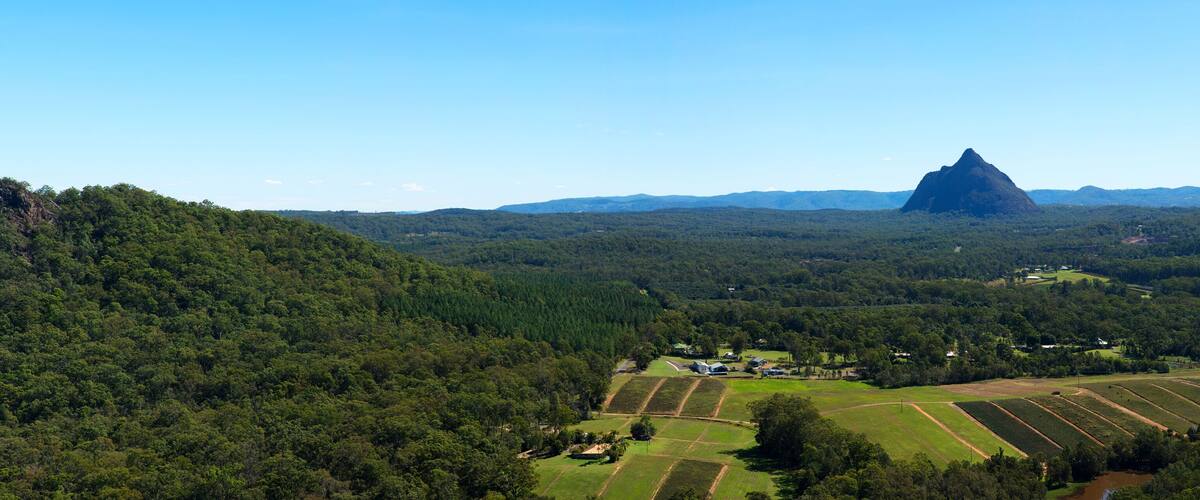 A rural landscape with rolling hills, a river, and two prominent rock formations.