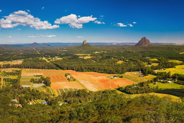 A rural landscape with fields, scattered houses, and prominent rock formations.
