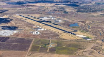 Vista aerea di un aeroporto con diverse piste di atterraggio, vie di rullaggio ed edifici terminal.