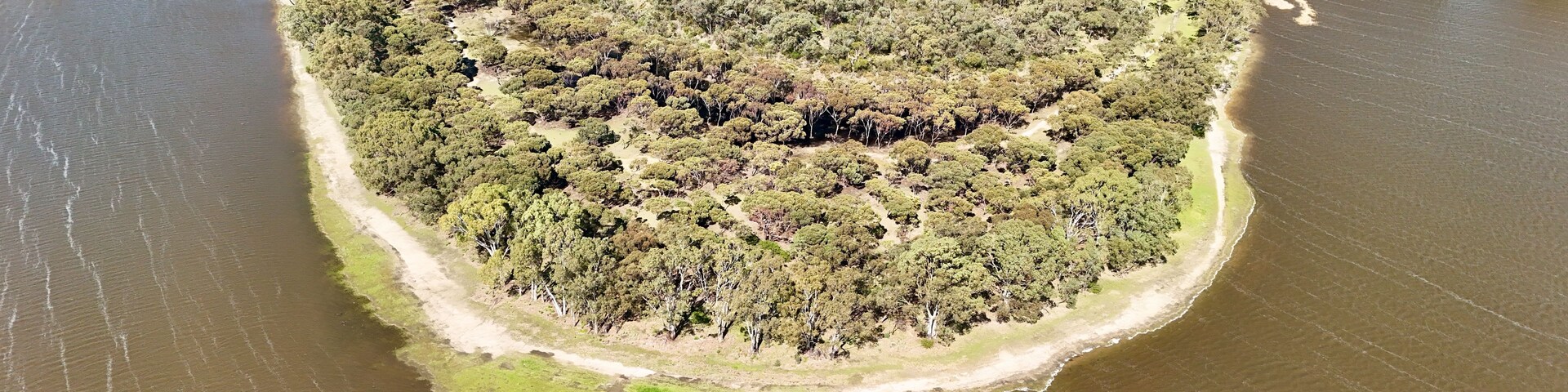 Vista aérea de uma ilha arborizada cercada por água.