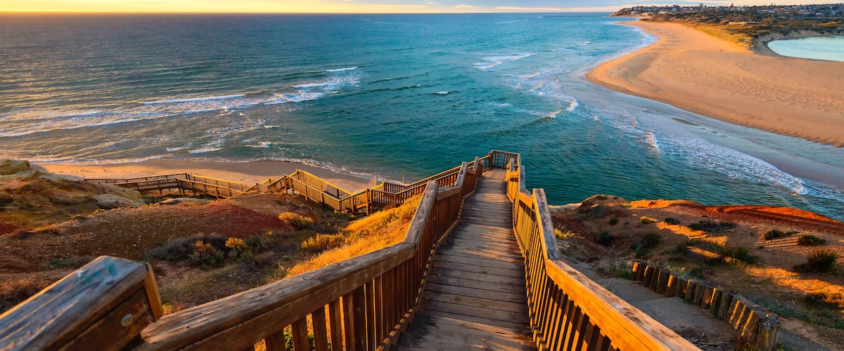 A wooden boardwalk leading to a beach with waves crashing onto the shore.