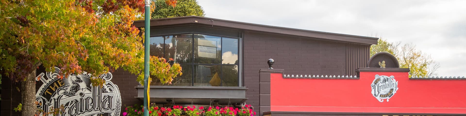 A brewery with a red exterior and hanging flower baskets.