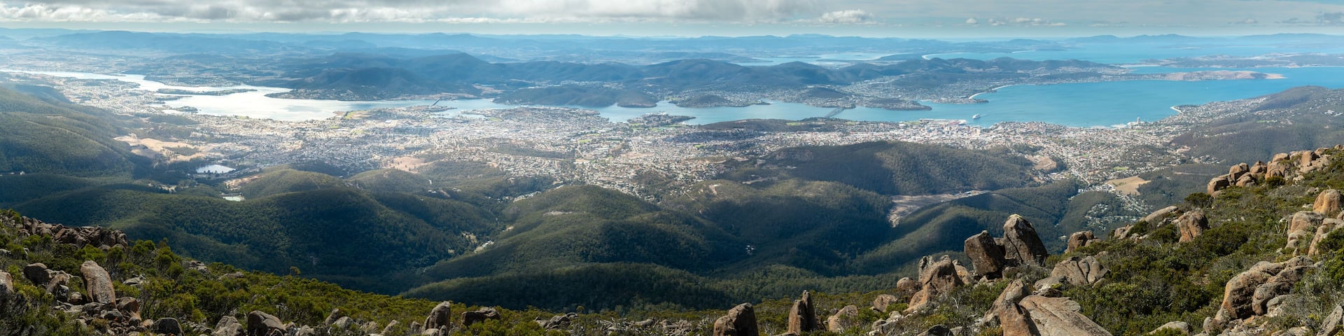 A mountainous landscape with a city and a large body of water.