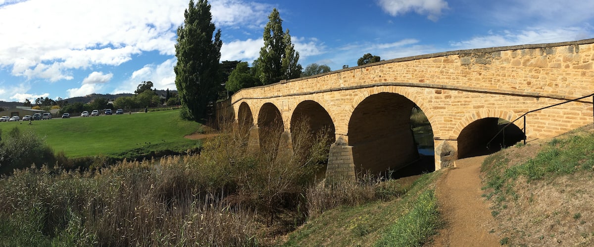 A stone viaduct with multiple arches over a grassy field.