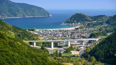 A coastal town with a bridge, beach, and forested hills.