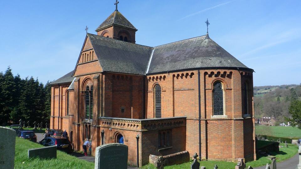 A brick church with a bell tower and a cemetery in the foreground.