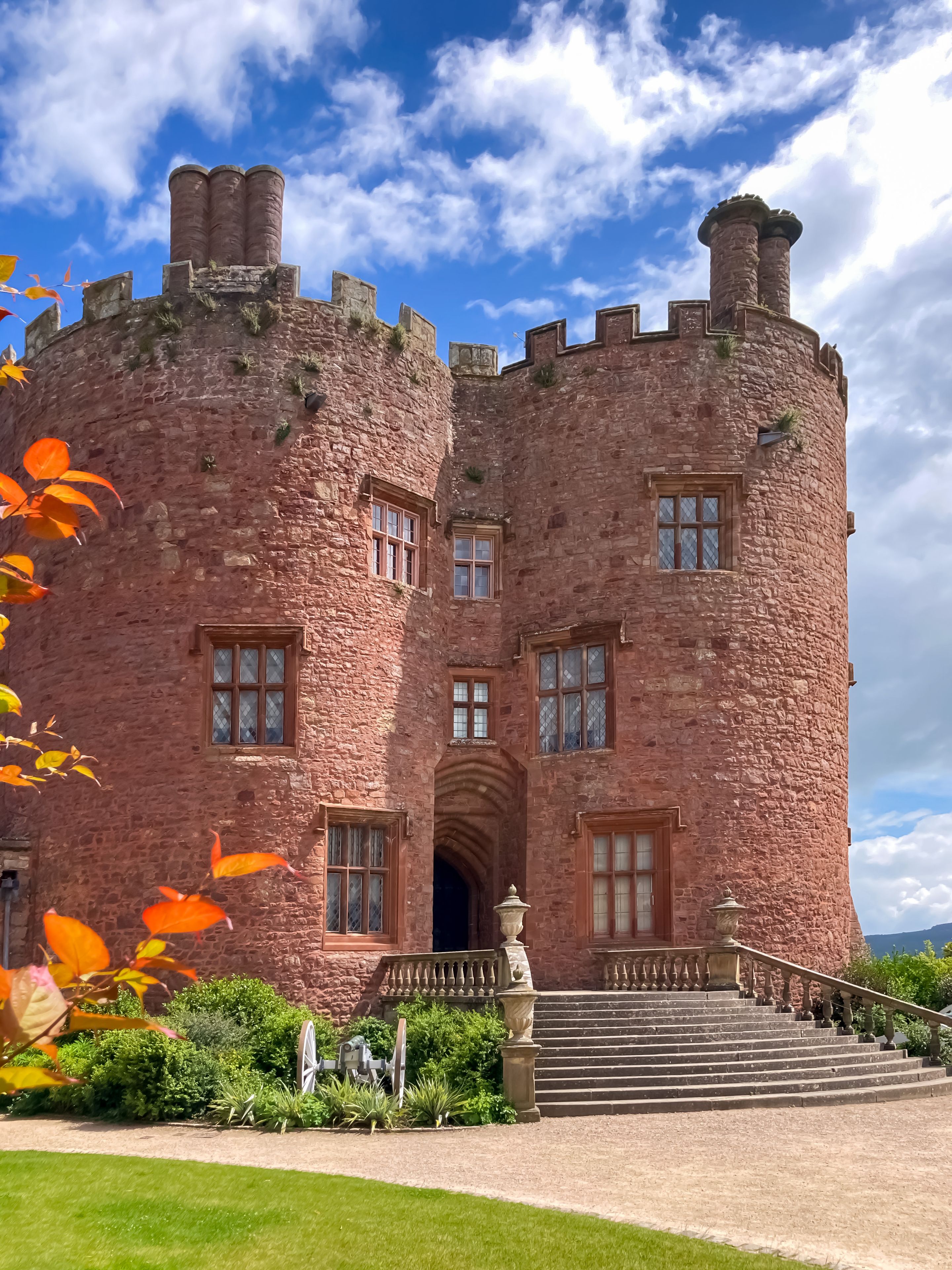 A castle with a stone facade, arched entrance, and a staircase leading to the main entrance.