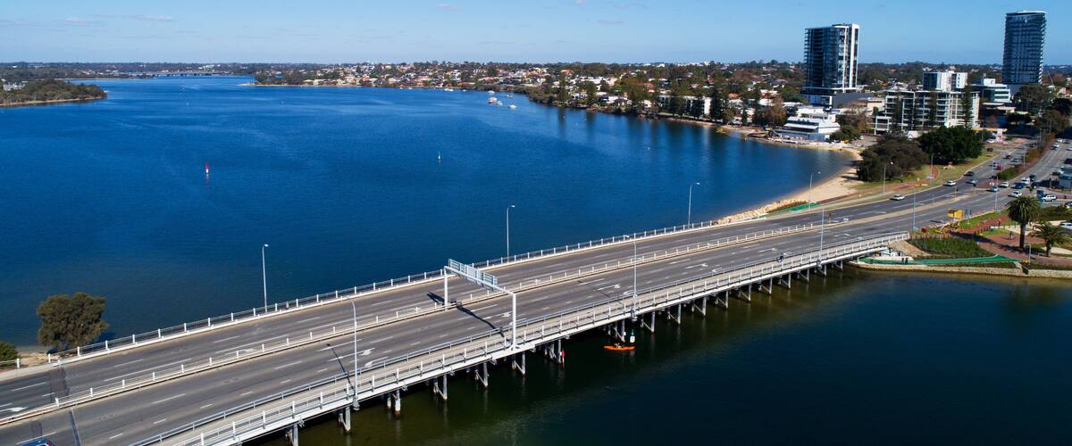 A bridge over a large body of water with a cityscape in the background.