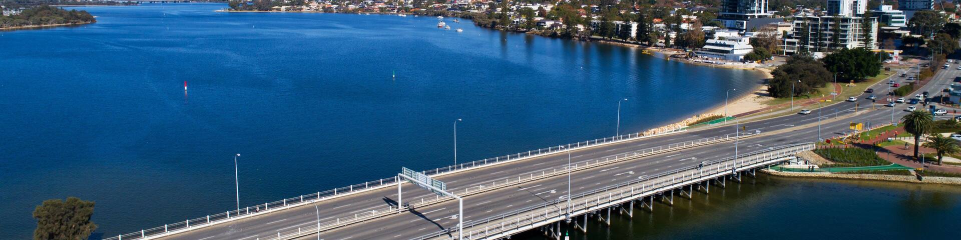 A bridge over a large body of water with a cityscape in the background.