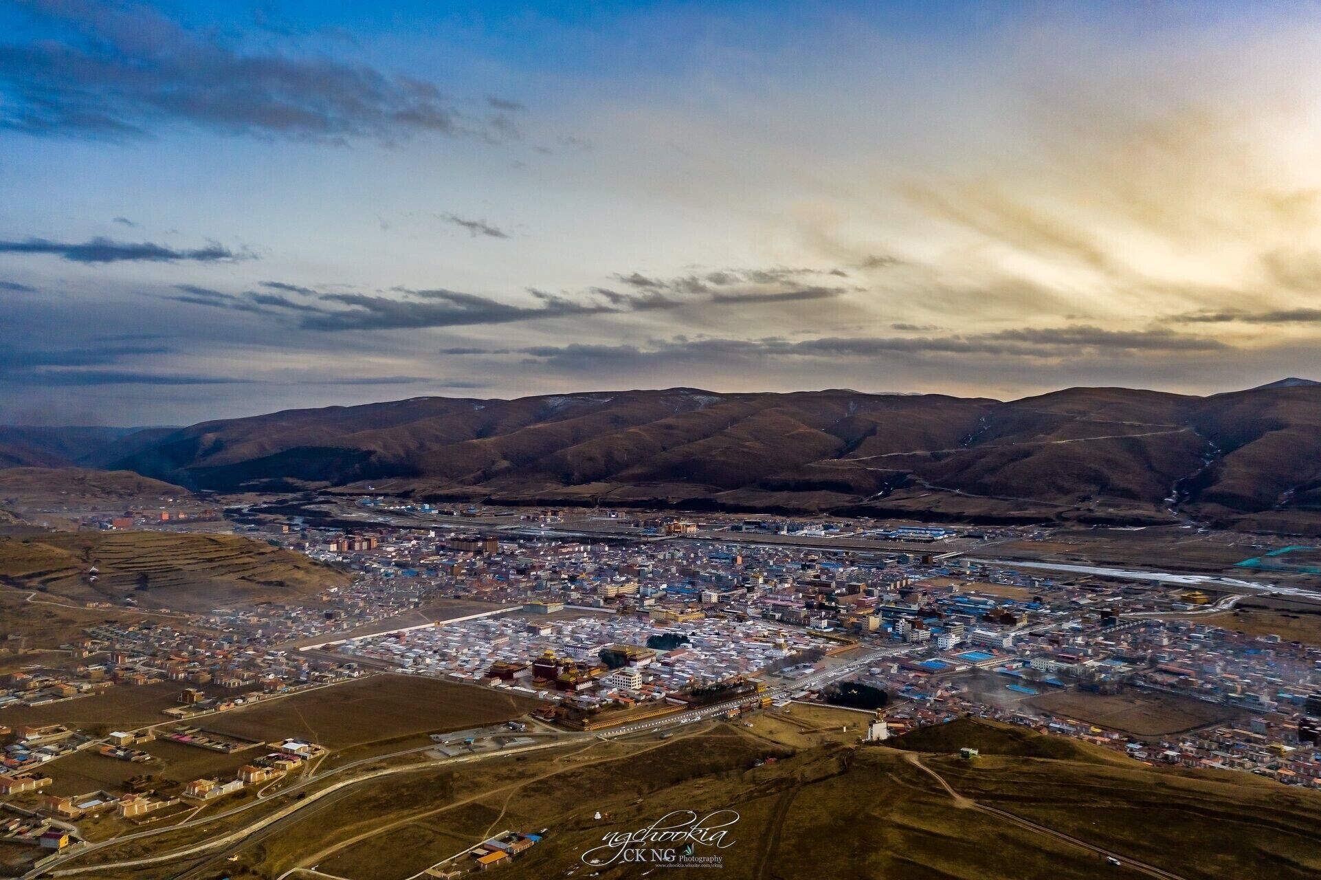 An aerial view of a city with a river running through it, surrounded by mountains.