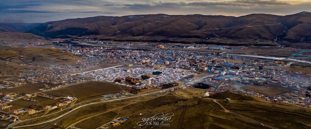 An aerial view of a city with a river running through it, surrounded by mountains.