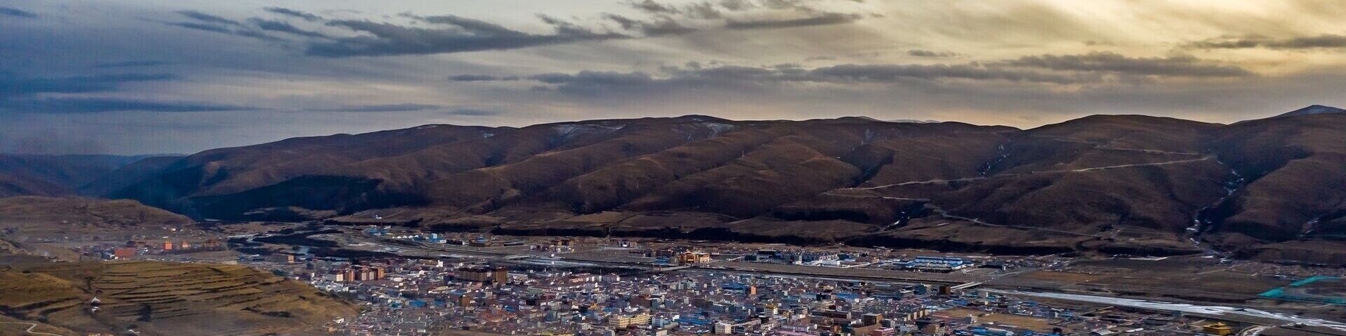 An aerial view of a city with a river running through it, surrounded by mountains.