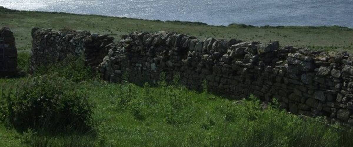 A stone wall and grassy area overlooking the sea.