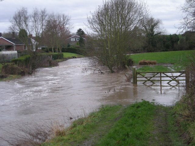 A flooded rural road with a wooden gate.