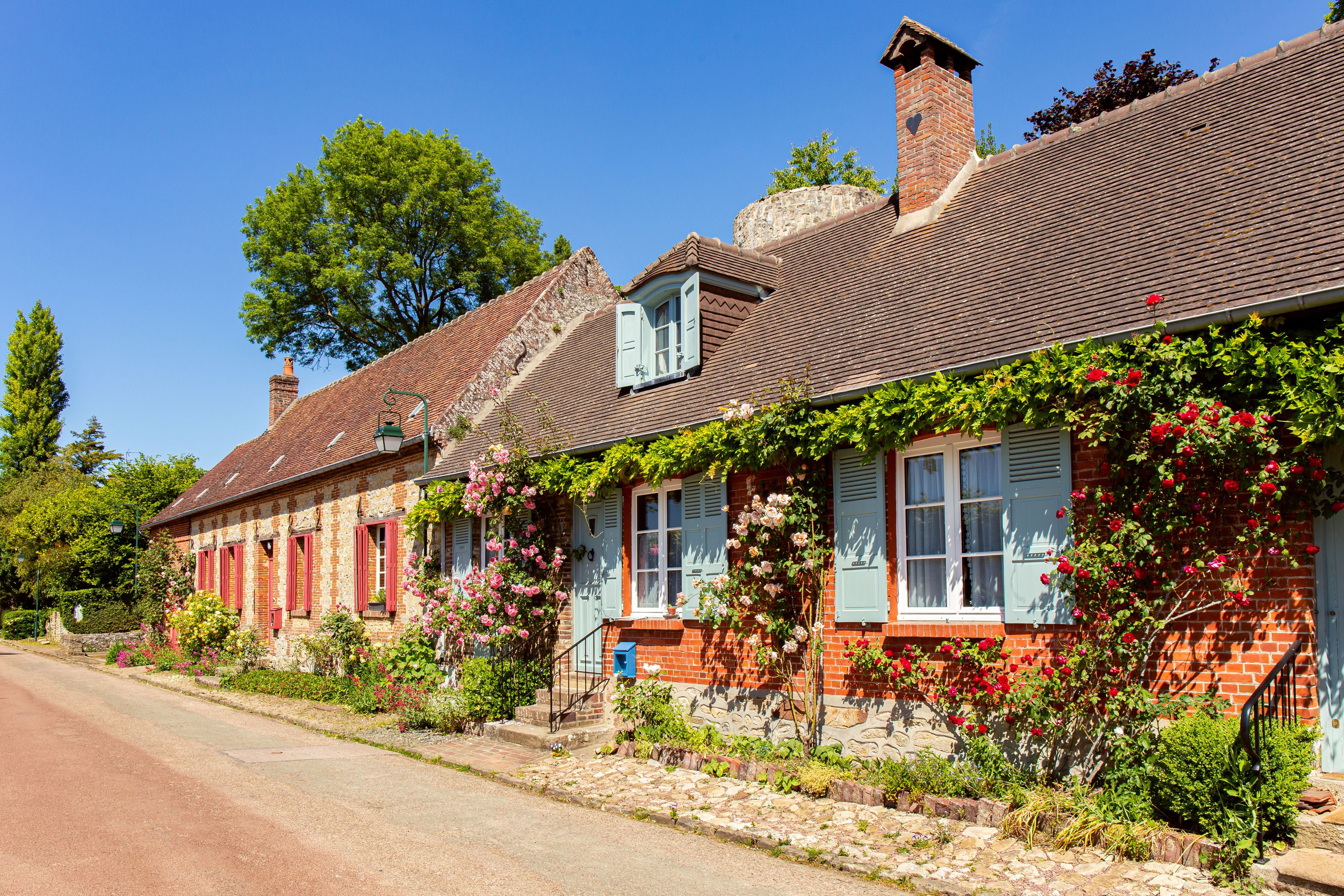 A row of traditional brick houses with red shutters and a clear blue sky.