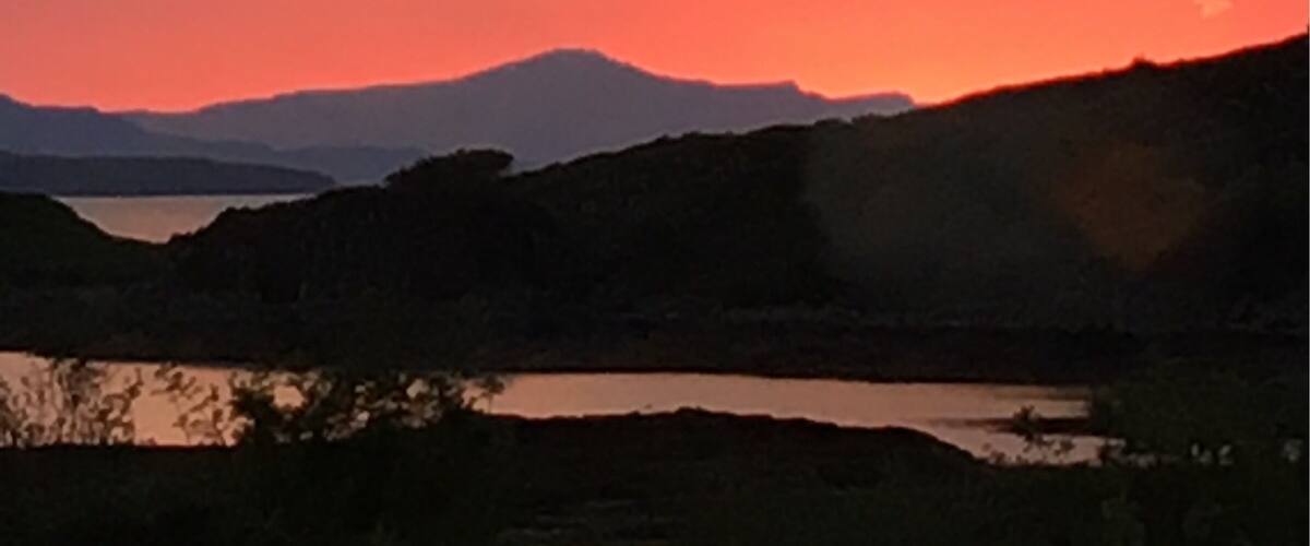 A sunset over a mountainous landscape with a lake.