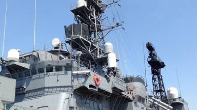 A large naval ship with multiple antennas, radar systems, and a lifebuoy.
