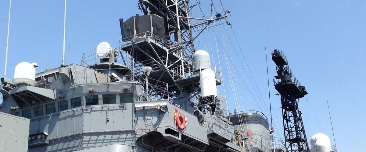 A large naval ship with multiple antennas, radar systems, and a lifebuoy.