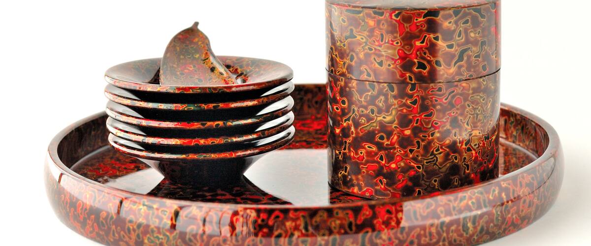 A stack of intricately designed plates and a matching cup on a reflective tray.