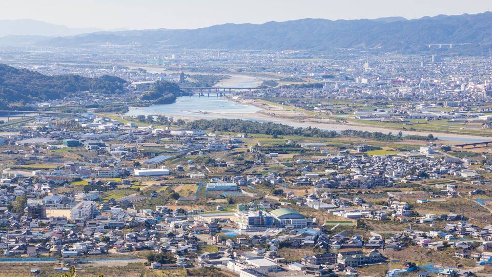 A cityscape with a river, bridges, and surrounding hills.