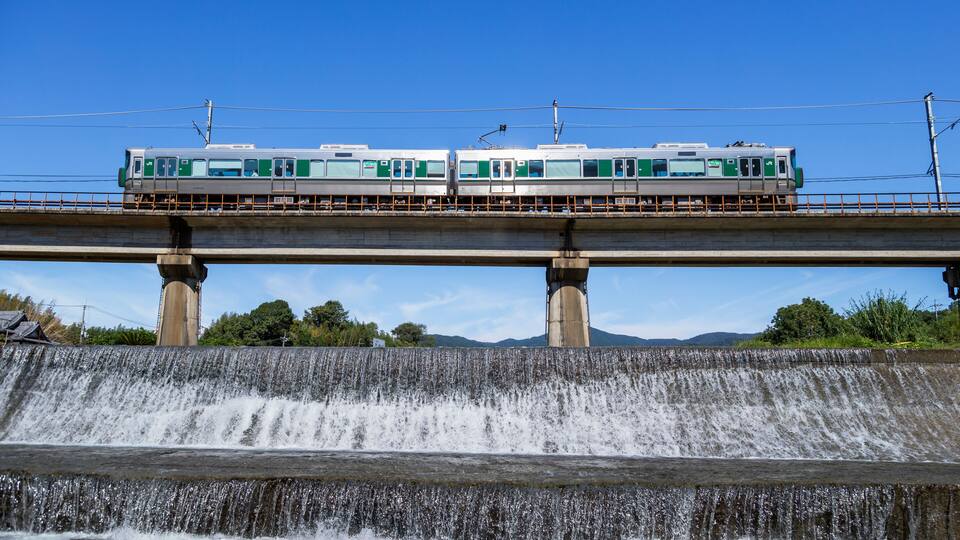 A train on an elevated track above a waterfall.