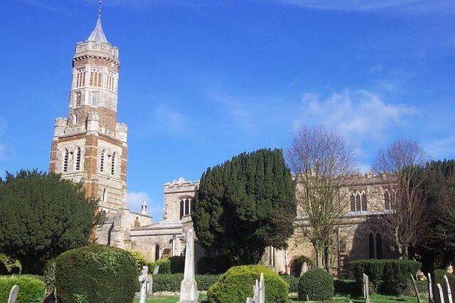 A historic church with a tall bell tower and well-maintained gardens.